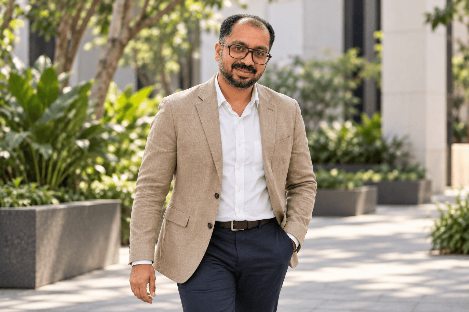 Dr. Kannan Dilip in a light jacket, walking through a leafy courtyard.